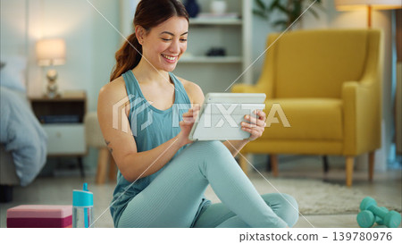 Fitness, internet and woman streaming on a tablet for training, yoga and exercise on the floor of her house. Happy, young and wellness girl with technology for a workout, cardio or video on pilates Fitness, internet and woman streaming on a tablet for training, yoga and exercise on the floor of her house. Happy, young and wellness girl with technology for a workout, cardio or video on pilates 139780976