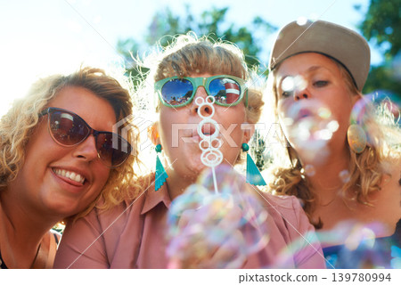 Women, friends and bubbles for blowing outdoor with sunglasses on weekend, break or holiday for relax and summer. People, happy and plastic wand or toy for playing or leisure on vacation or adventure Women, friends and bubbles for blowing outdoor with sunglasses on weekend, break or holiday for relax and summer. People, happy and plastic wand or toy for playing or leisure on vacation or adventure 139780994
