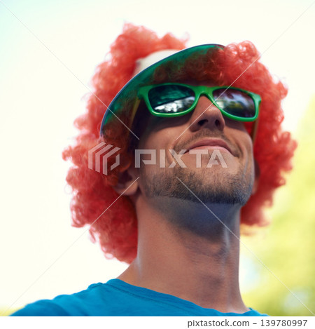 Man, wig and sunglasses with nature, sky and festival for fun, joy and celebration. Person, summer and concert with low angle, smile and happy for event, party or sunshine for celebration and closeup Man, wig and sunglasses with nature, sky and festival for fun, joy and celebration. Person, summer and concert with low angle, smile and happy for event, party or sunshine for celebration and closeup 139780997