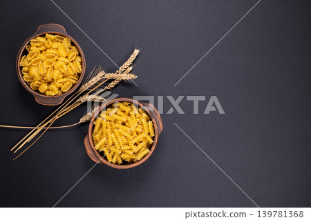 Dry pasta varieties in ceramic bowls with wheat Dry pasta varieties in ceramic bowls with wheat 139781368