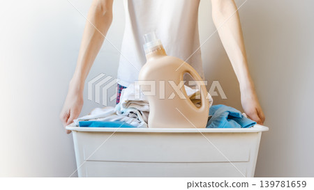 Teen Doing Laundry With Detergent Bottle And Full Basket At Home Teen Doing Laundry With Detergent Bottle And Full Basket At Home 139781659