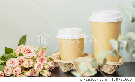 Two Coffee Cups In Craft Paper Holder With Pink Roses On Table Two Coffee Cups In Craft Paper Holder With Pink Roses On Table 139781660