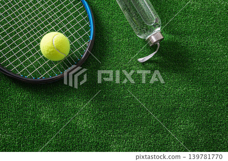 Tennis racket and reusable water bottle on green grass court 139781770