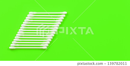 Cotton sticks / ear swabs arranged in trapezoid on green table, view from above, space for text right side 139782011
