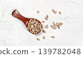 Peeled sunflower seeds in small wooden scoop, placed on white stone like board, view from above 139782048