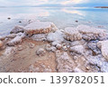 Sand and stones covered with crystalline salt on shore of Dead Sea, clear water background - typical morning scenery at Ein Bokek beach, Israel 139782051