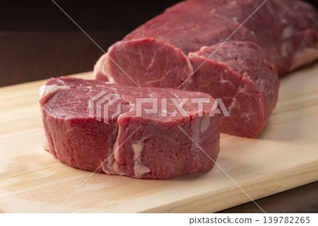 A beef fillet steak is placed on a wooden cutting board. A beef fillet steak is placed on a wooden cutting board. 139782265