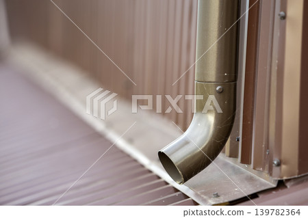 Close-up of brown new gutter metal system pipe on wall. Drain protection, professional work concept. 139782364
