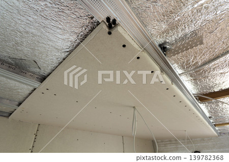 Room under construction with silver aluminum insulation foil and drywall on walls and ceiling. 139782368