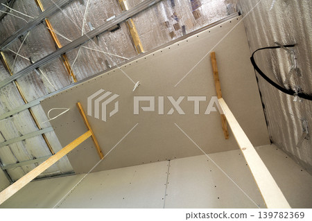 Room under construction with silver aluminum insulation foil and drywall on walls and ceiling. Room under construction with silver aluminum insulation foil and drywall on walls and ceiling. 139782369