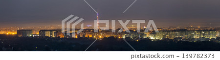 Wide panorama, aerial night view of modern tourist Ivano-Frankivsk city, Ukraine. Scene of bright lights of tall buildings, high television tower and green suburbs on Carpathian mountains background. Wide panorama, aerial night view of modern tourist Ivano-Frankivsk city, Ukraine. Scene of bright lights of tall buildings, high television tower and green suburbs on Carpathian mountains background. 139782373