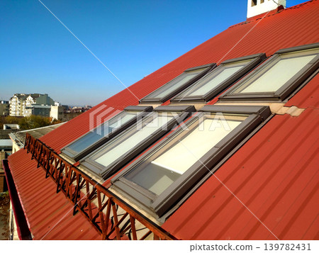 Red tiled house roof with attic windows. Roofing construction, window installation, modern architecture concept. Red tiled house roof with attic windows. Roofing construction, window installation, modern architecture concept. 139782431