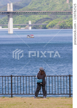 A woman photographs a lake in early summer at Lake Yamba-Agatsuma. A woman photographs a lake in early summer at Lake Yamba-Agatsuma. 139782525