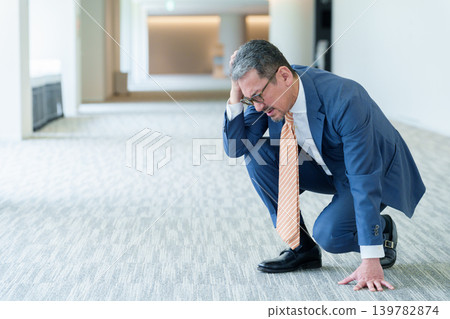 一名商人痛苦地摀著頭。 一名商人痛苦地摀著頭。 139782874