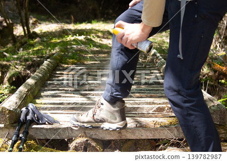 A Japanese man sprays insect repellent on his trekking shoes and trousers. A Japanese man sprays insect repellent on his trekking shoes and trousers. 139782987
