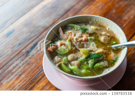 Traditional Thai kaeng liang soup shrimp mixed vegetables herbs served hot in bowl on wooden table healthy local cuisine 139783538