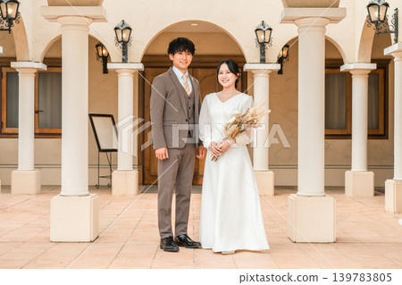 身著婚紗的新郎新娘在婚禮教堂裡手捧乾燥花和花環。 身著婚紗的新郎新娘在婚禮教堂裡手捧乾燥花和花環。 139783805