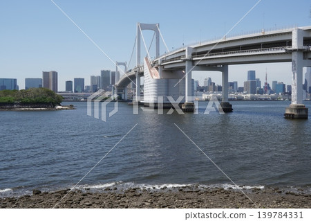 A view of Tokyo Bay, the Rainbow Bridge, and the skyscrapers of Minato Ward from Daiba Park (Third Daiba) on a clear day. A view of Tokyo Bay, the Rainbow Bridge, and the skyscrapers of Minato Ward from Daiba Park (Third Daiba) on a clear day. 139784331