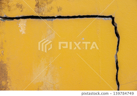 Full frame shot of cracked yellow wall. Wider cracks often represent serious structural damage and can cause serious issues. Full frame shot of cracked yellow wall. Wider cracks often represent serious structural damage and can cause serious issues. 139784749