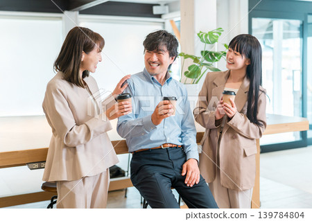Businessman and businesswoman chatting over coffee in the office Businessman and businesswoman chatting over coffee in the office 139784804
