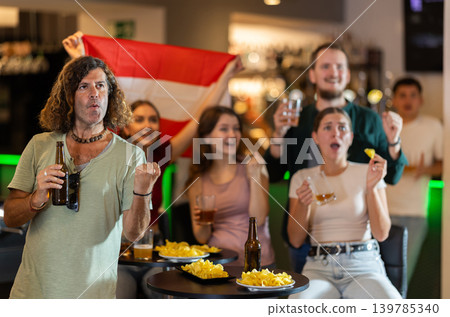 Men and women supporting Austria sports team in pub together. Group of friends raising Austria flag Men and women supporting Austria sports team in pub together. Group of friends raising Austria flag 139785340