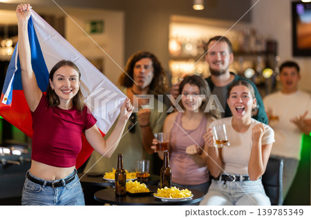 Men and women supporting Czech sports team in pub together. Group of friends raising Czech flag Men and women supporting Czech sports team in pub together. Group of friends raising Czech flag 139785349