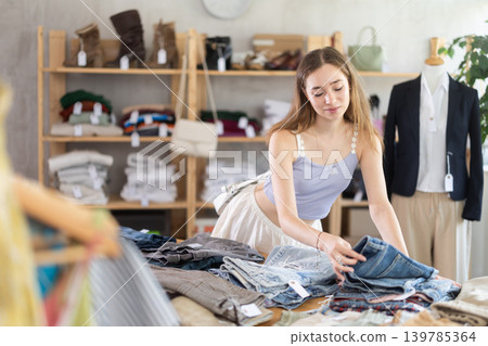 Selective young woman choosing pantaloons in clothing store Selective young woman choosing pantaloons in clothing store 139785364