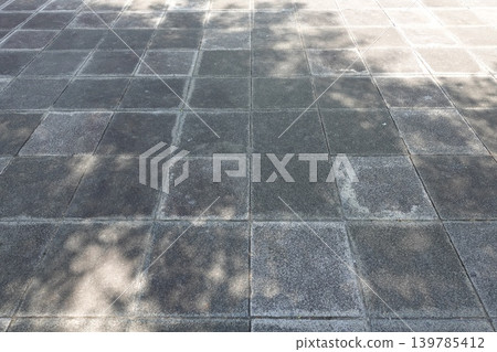 A background image featuring dappled sunlight reflecting on gray cobblestones and a sense of perspective. A background image featuring dappled sunlight reflecting on gray cobblestones and a sense of perspective. 139785412