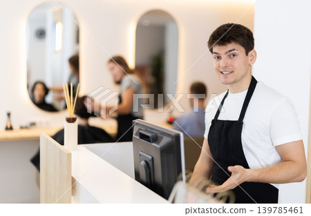 Young guy at cash register in beauty salon Young guy at cash register in beauty salon 139785461