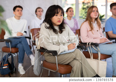 High school students sit at their desks and listen carefully to the teacher at lesson at school High school students sit at their desks and listen carefully to the teacher at lesson at school 139785578