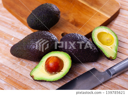 Whole and cut in half avocados on wooden background Whole and cut in half avocados on wooden background 139785621