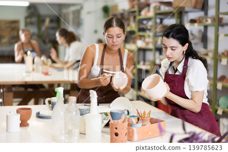 Girls processing clay bowls in carpentry workshop Girls processing clay bowls in carpentry workshop 139785623
