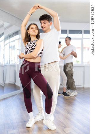 Dance training in group - young men and women dance salsa or bachata in dance studio Dance training in group - young men and women dance salsa or bachata in dance studio 139785624