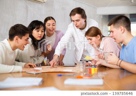 Young guys and girls playing board game together Young guys and girls playing board game together 139785646