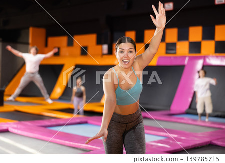 Young woman in sport clothes high jumping in trampoline arena Young woman in sport clothes high jumping in trampoline arena 139785715
