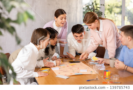 Group of positive younger people playing tabletop game Group of positive younger people playing tabletop game 139785743