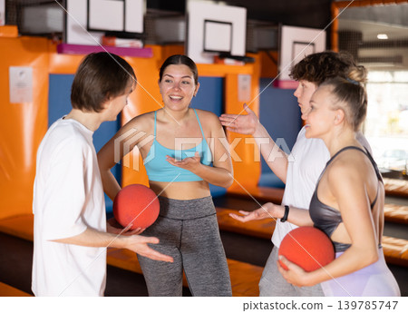 Two women and two teenager guys communicate in trampoline center Two women and two teenager guys communicate in trampoline center 139785747