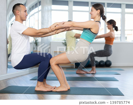Lovers of active lifestyle pair yoga doing double power pair pose in gym 139785774