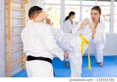 arate trainer helps woman learn how to kick during karate training arate trainer helps woman learn how to kick during karate training 139785788