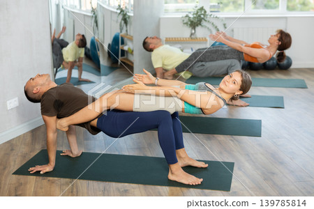 Lovers of active lifestyle perform doing double reverse plank support pose in gym Lovers of active lifestyle perform doing double reverse plank support pose in gym 139785814