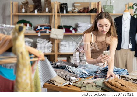 Selective young woman scanning QR-code on pantaloons in clothing store Selective young woman scanning QR-code on pantaloons in clothing store 139785821