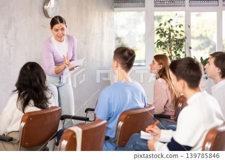 While working in classroom, female teacher answers questions that students had while studying new lesson While working in classroom, female teacher answers questions that students had while studying new lesson 139785846