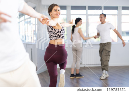 Group of young active sports people practicing rock and roll dance in dance hall 139785851
