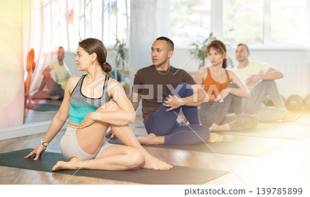 Portrait of people practicing Matsyendrasana known as Lord of Fishes Pose during group yoga training Portrait of people practicing Matsyendrasana known as Lord of Fishes Pose during group yoga training 139785899