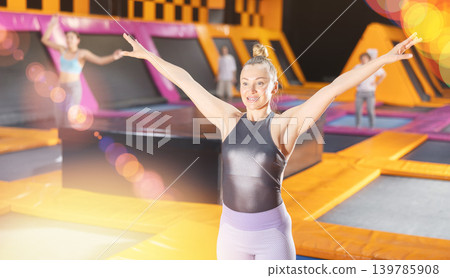 Middle-aged woman in sport clothes doing exercises in trampoline arena Middle-aged woman in sport clothes doing exercises in trampoline arena 139785908