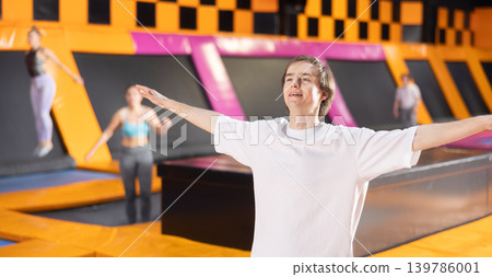 Young man in sport clothes doing exercises in trampoline arena 139786001