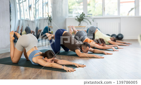 Group yoga class in gym - men and women meditate in Ashtanga Namaskarasana pose Group yoga class in gym - men and women meditate in Ashtanga Namaskarasana pose 139786005