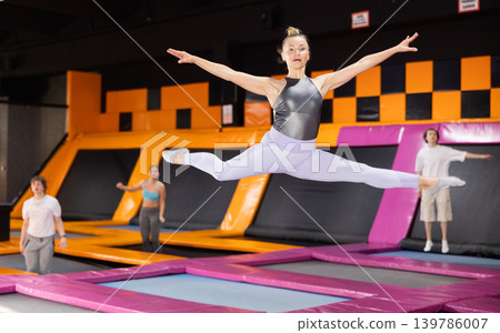 Emotive adult woman having great time while jumping on colorful trampoline in entertainment center Emotive adult woman having great time while jumping on colorful trampoline in entertainment center 139786007