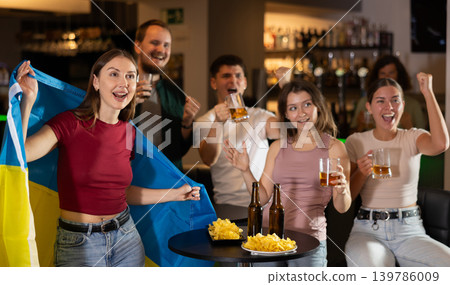 Group of fans in bar with Ukrainian flag Group of fans in bar with Ukrainian flag 139786009