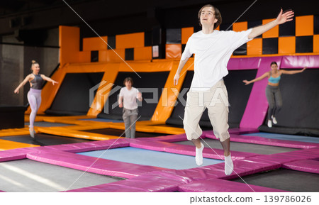 Young guy trains jumping in trampoline center 139786026